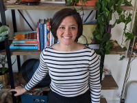 Female student nurse standing in front of bookshelf.